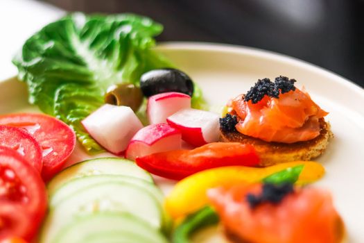 Appetiser platter with salmon, black caviar and sliced fresh vegetables for hospitality and gastronomy