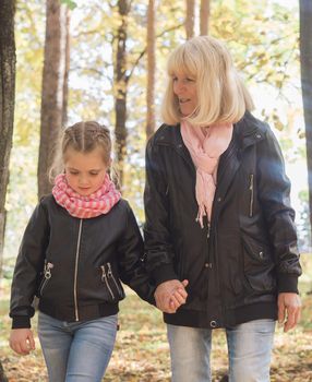 Grandmother with granddaughter in autumn park. Generation and family concept.
