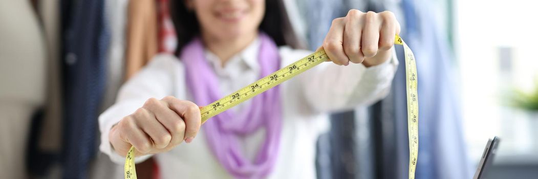Woman seamstress holds centimeter for taking measurements in atelier