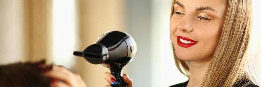 Woman hairdresser doing styling with hairdryer to man