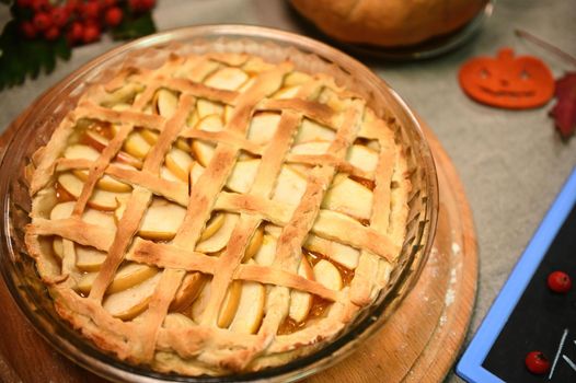 Homemade delicious yummy festive pumpkin pie with caramelized apples, with flaky crust lattice for Thanksgiving dinner.