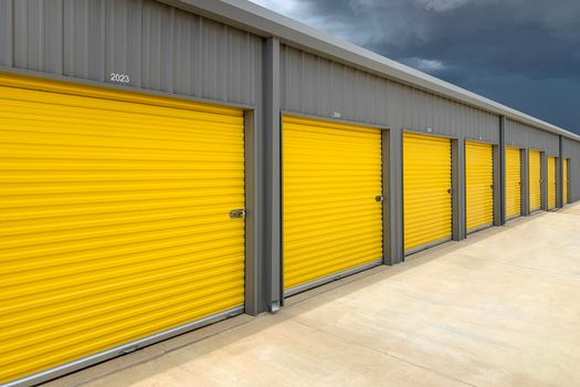 Exterior of a commercial warehouse with yellow roller doors, garages, self storage facilities.