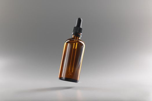 Brown bottle with a pipette on a gray background