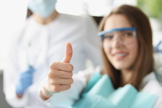 A woman at the dentist shows a thumbs up gesture