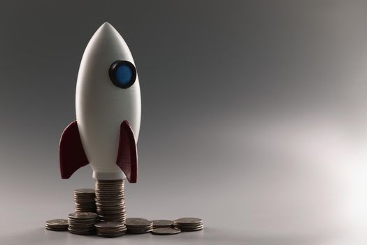 Plastic rocket on top of a stack of coins, close-up