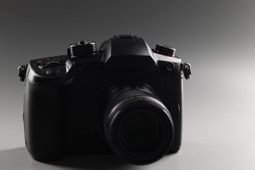 Black photo camera on a gray background, lens
