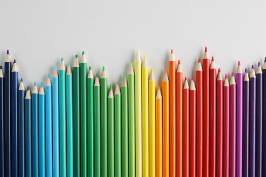 Colored pencils vertically in a row in a wave, different in height