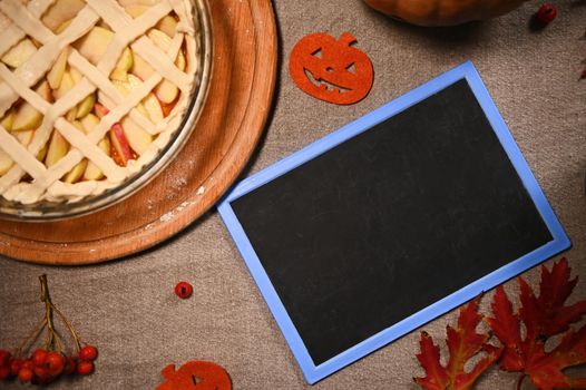 Top view freshly baked Thanksgiving pie with pumpkin and apples and crispy crust lattice and blackboard with copy space