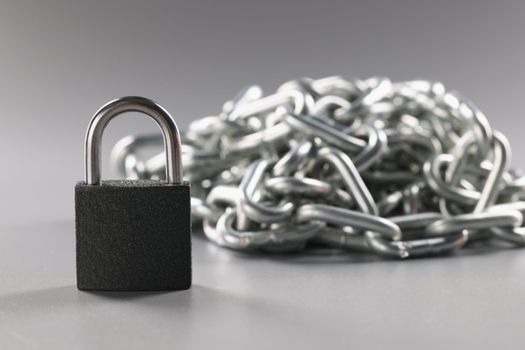 Padlock and metal chains on a gray background