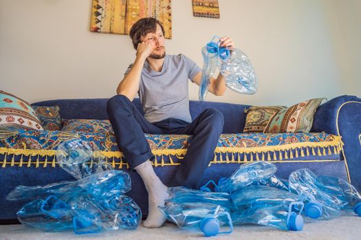 Young caucasian man hamong empty plastic bottles to recycle with sad expression