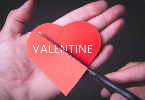 Valentine.Broken heart. Scissors cut a paper heart with an inscription.