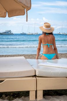 Lonely woman in bikini looking at the sea on a bed