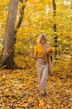Walking woman on a fall day in the beautiful autumn park. Season and loneliness concept