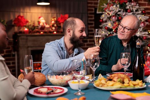 Man proposing christmas toast, saying wishes at festive dinner