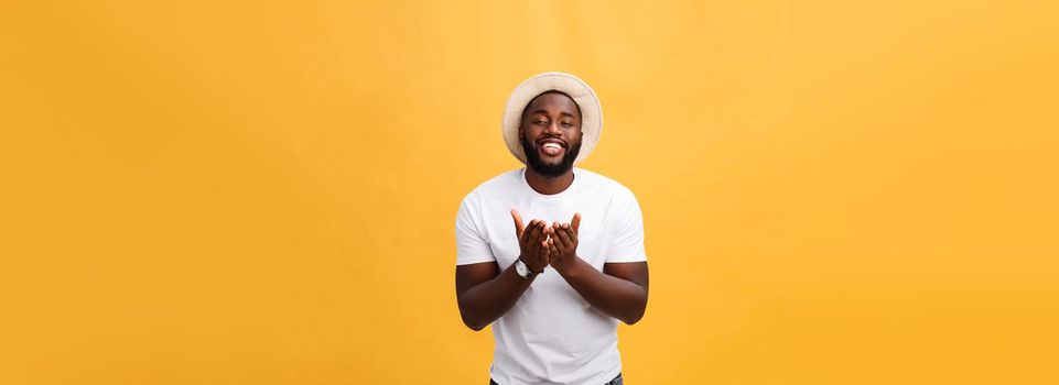 Portrait of handsome young african guy smiling in white t-shirt on yellow background