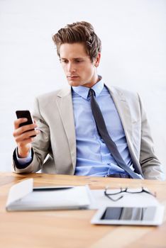 Reading an urgent text. A young businessman reading a text message from his desk.