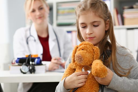 Little girl child holding toy and stethoscope at reception of pediatrician