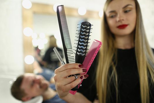 Hairdresser woman holding comb and scissors in barbershop