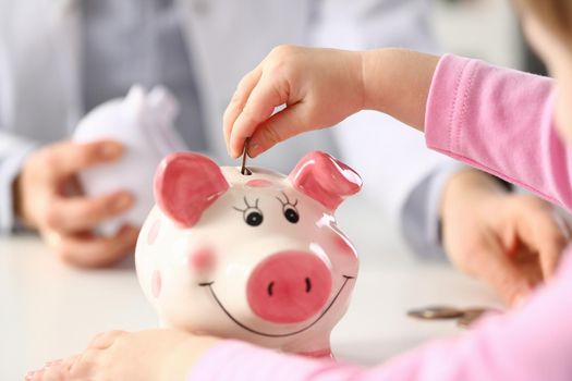 Child hand put a money coin in piggy bank to save money wealth
