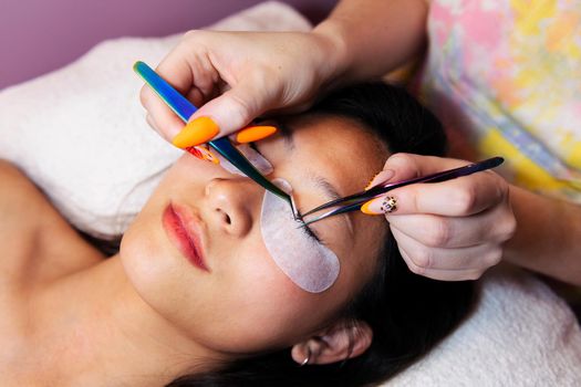 beautician applies eyelash extensions with tweezer
