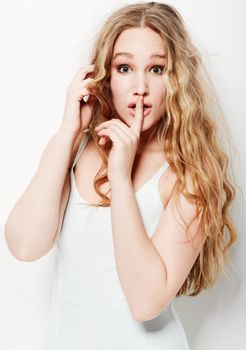 Ssh, dont tell a soul. Young woman with her finger on her lips against a white background.
