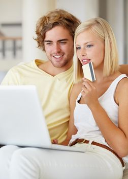 Buying online is fast and easy. A happy young couple buying online with their credit card.