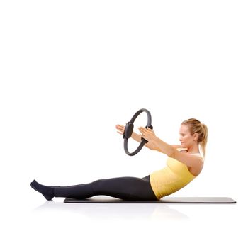 Pilates ring requires balance and strength. A pretty young blonde performing the roll up exercise with her pilates ring.