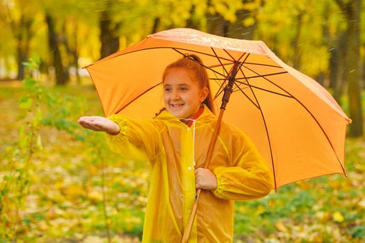 happy kid catching rain drops in Autumn park
