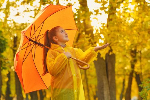 happy kid catching rain drops in Autumn park