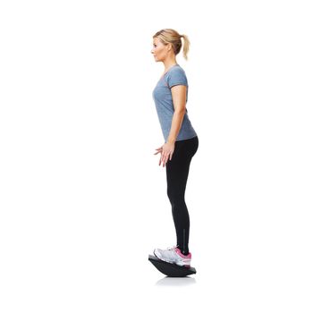 Balancing on her bosu - Health Fitness. A pretty young blond standing on a balance board while isolated on white.