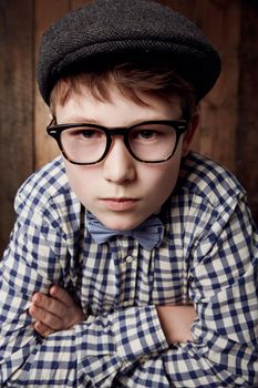 Lets get serious...Young boy in retro clothing wearing spectacles with a stern expression.