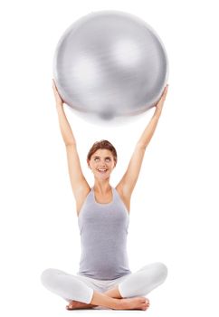 Maintaining her health through the pregnancy. A pretty pregnant woman lifting a medicine ball on a white background.