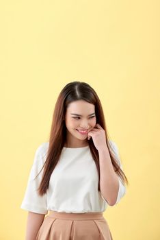 beautiful young woman with long black hair posing on yellow background