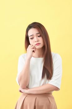 confused young girl thinking on yellow background