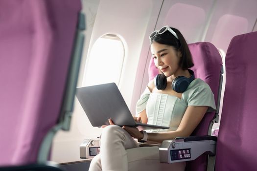 Attractive asian woman passenger of airplane using laptop computer and wifi on board. tourism traveler concept.