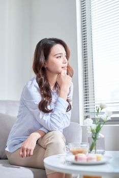 Woman sitting on window sill, looking out of window 