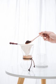 fill grind coffee in filter with wooden spoon