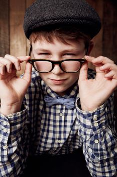 Im not sure I believe you...Young boy in retro clothing wearing spectacles with a suspicious expression.