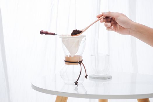 fill grind coffee in filter with wooden spoon
