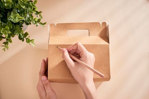  Cropped image of woman writing best wishes on box with present