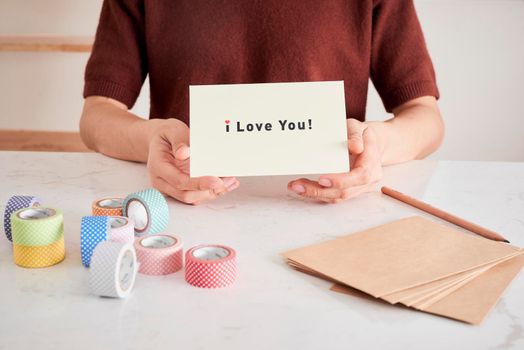 hands holding greeting card with phrase letters "i love you" prepared for sweetheart