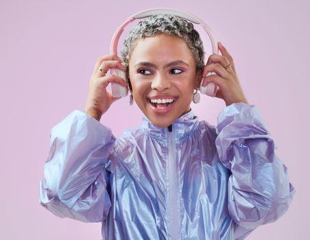 Black woman and holding headphones in studio for music streaming entertainment with pink wall. Mockup pink background with happy, funky and edgy african fashion girl enjoying bluetooth audio.