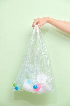 Female hand holding a waste bag isolated on white background.