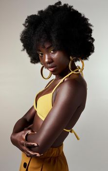 Black woman, confidence and stylish with yellow fashion being trendy, edgy and with attitude. African American female with afro, relax against grey studio background, black girl magic and being cool