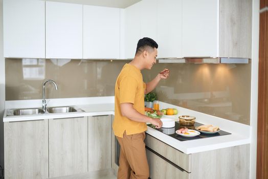 Happy Asian man preparing food in the kitchen at home.