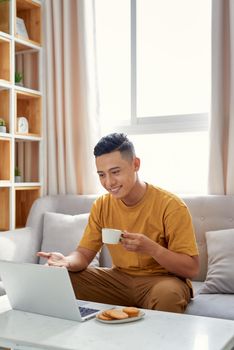 happy young Man sitting in sofa and using laptop