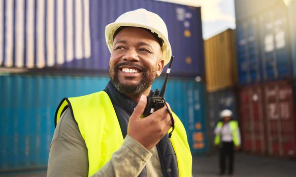 Man in logistics talking on radio, communication in shipping and transportation industry with a smile. Organization of commercial cargo, e-commerce containers and supply chain management of shipyard