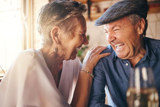 Senior, couple and laugh after comic joke together in restaurant for bonding time. Smile, man and woman in retirement laughing at funny conversation with love, happiness and comedy in cafe with wine