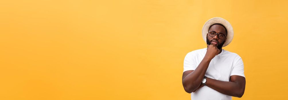 Portrait of a pensive afro american man in glasses looking up at copyspace isolated on a yellow background