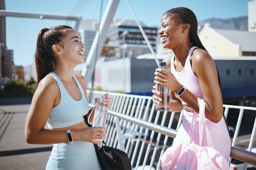 Diversity, fitness and friends laughing while drinking water to hydrate after training, exercise and running outdoors in USA. Smile, healthy and happy black woman enjoys a funny joke with Latino girl